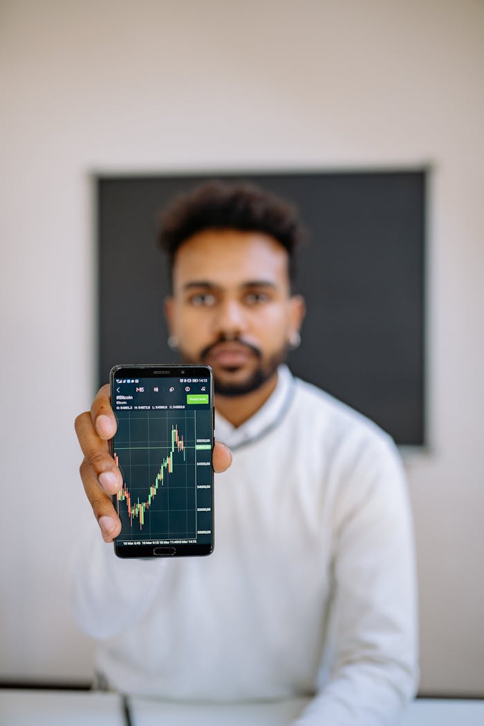 » pexels photo 7691737 1 Man holding smartphone with stock market chart, focusing on financial growth.